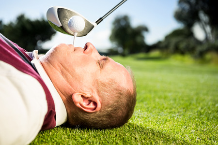 Golfer holding tee in his teeth on a sunny day at the golf courseの写真素材