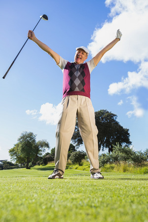 Excited golfer cheering and looking at camera on a sunny day at the golf courseの写真素材