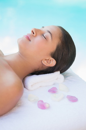 Calm brunette lying on towel with rose petals outside at the spaの写真素材
