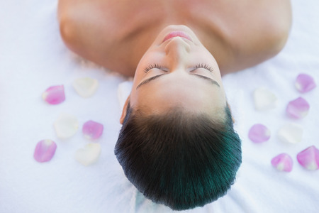 Calm brunette lying on towel with rose petals outside at the spaの写真素材