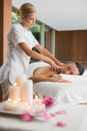 Smiling brunette getting a shoulder massage at the health spaの写真素材