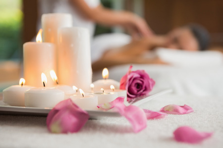 Candles and rose petals on massage table at the health spaの写真素材