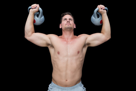 Strong bodybuilder lifting up kettlebells on black background
