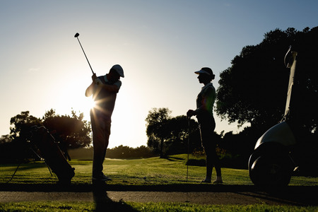 Golfing couple teeing off for the day on a sunny morning at the golf courseの写真素材