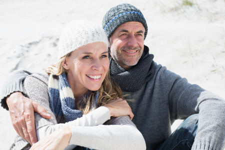 Attractive couple smiling on the beach in warm clothing on a bright but cool dayの写真素材