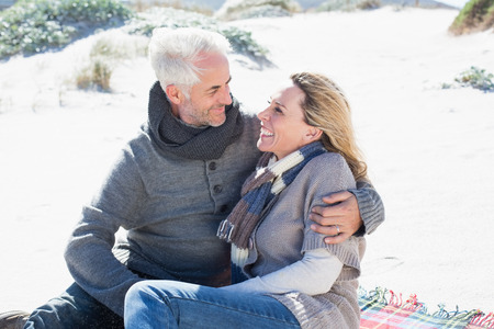 Carefree couple having picnic on the beach on a bright but cool dayの写真素材