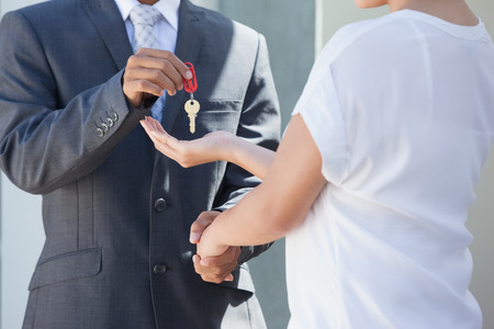 Estate agent giving house key to buyer outside a houseの写真素材