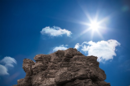 Digitally generated large rock overlooking bright blue sky