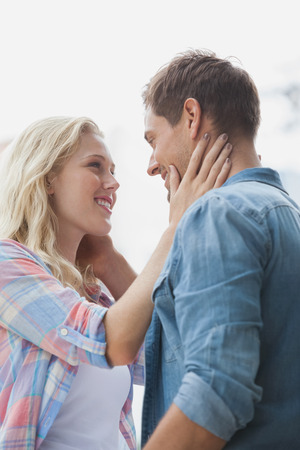Cute young couple standing and facing each other on a sunny day in the cityの写真素材