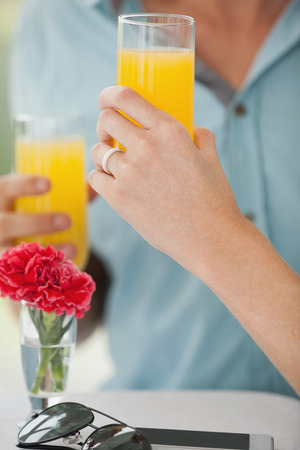 Cute couple sitting in cafe drinking orange juice on a sunny day in the cityの写真素材