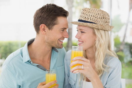 Hip young couple drinking orange juice together on the cafe terrace on sunny dayの写真素材