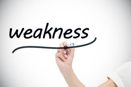Businesswoman writing the word weaknesses against white background with vignetteの写真素材