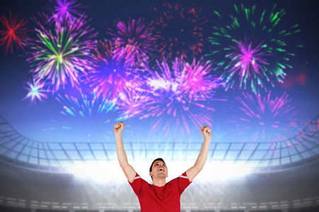 Excited football player cheering against fireworks exploding over football stadiumの写真素材