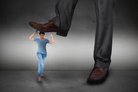 Composite image of businessman stepping on girl on grey backgroundの写真素材