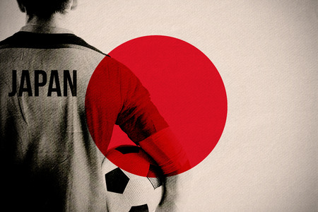 Japan football player holding ball against japan national flagの写真素材