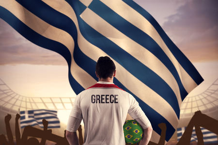 Greece football player holding ball against large football stadium under cloudy blue skyの写真素材