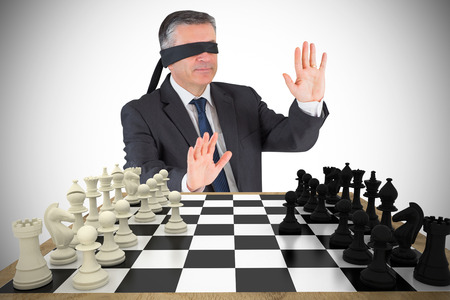 Composite image of mature businessman in a blindfold with chessboardの写真素材