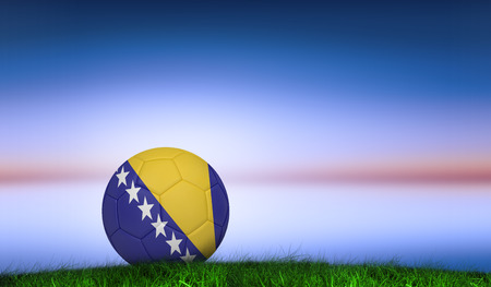 Football in bosnia and herzegovina colours  against green grass under blue and purple skyの写真素材