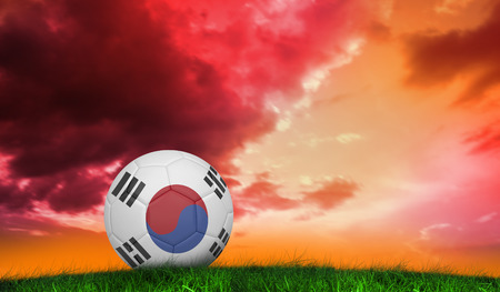 Football in south korea colours  against green grass under red and purple skyの写真素材
