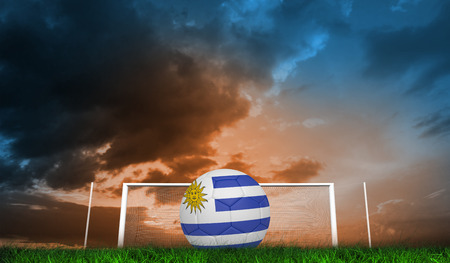 Football in uruguay colours  against green grass under blue and orange skyの写真素材
