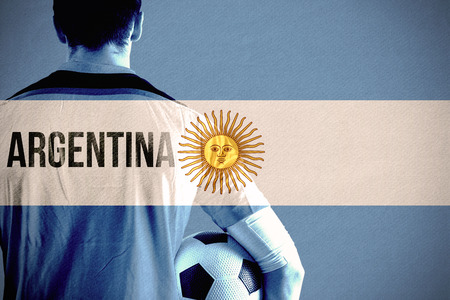 Argentina football player holding ball against argentina national flagの写真素材