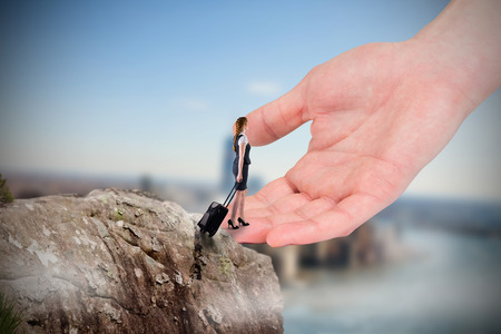 Redhead businesswoman pulling her suitcase to large hand against large rock overlooking foggy cityの写真素材