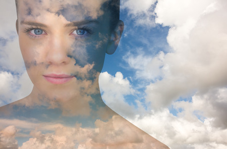 Serious blonde natural beauty against blue sky with white cloudsの写真素材