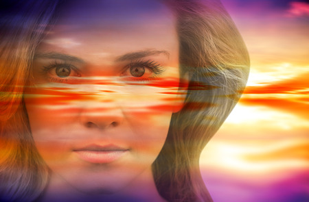 Serious blonde natural beauty against purple sky with orange cloudsの写真素材