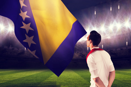 Handsome football fan looking ahead against large football stadium under night skyの写真素材