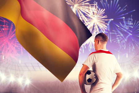 Football player holding the ball against fireworks exploding over football stadiumの写真素材