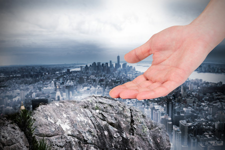 Businesswomans hand presenting against large rock overlooking huge cityの写真素材