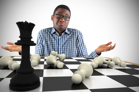 Composite image of young businessman shrugging shoulders with chessboardの写真素材