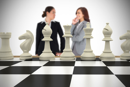 Composite image of businesswomen and chess pieces against white background with vignetteの写真素材