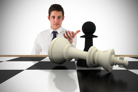Businessman standing with hand out with chessboard against white background with vignetteの写真素材