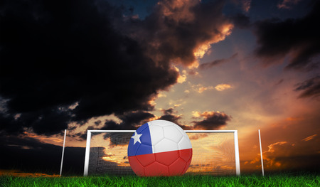 Football in chile colours against green grass under dark blue and orange skyの写真素材