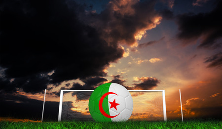 Football in algeria colours against green grass under dark blue and orange skyの写真素材