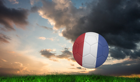 Football in france colours against green grass under blue and orange skyの写真素材