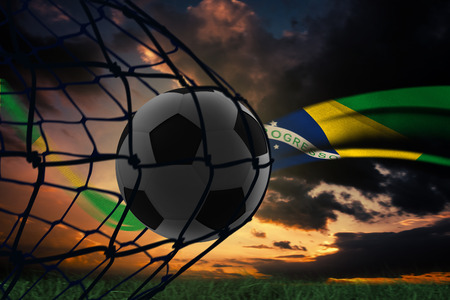 Composite image of football in back of the net against brazilian flag flowの写真素材