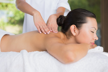 Content brunette getting a back massage at the spaの写真素材
