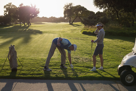 Golfing couple teeing off for the day on a sunny morning at the golf courseの写真素材