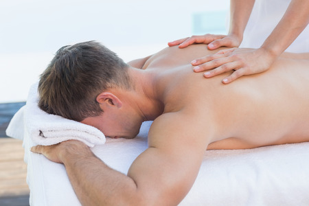 Handsome man getting a massage poolside outside at the spaの写真素材