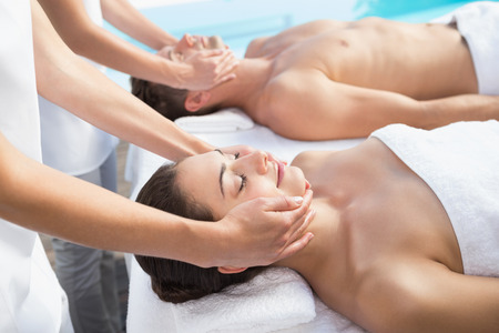 Content couple enjoying head massages poolside outside at the spaの写真素材