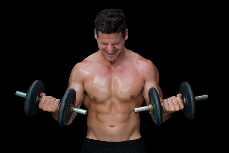 Strong crossfitter lifting up heavy black dumbbells on black background