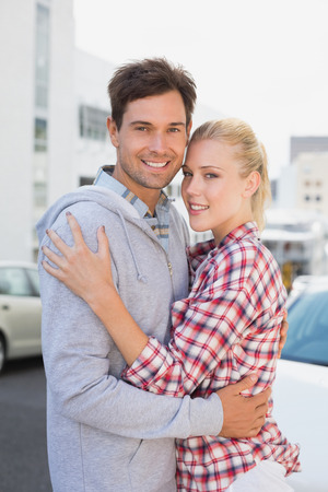 Hip young couple hugging smiling at camera on a sunny day in the cityの写真素材