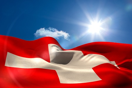 Digitally generated swiss flag rippling against blue skyの写真素材