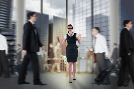 Composite image of redhead businesswoman in a blindfold walking through crowdの写真素材