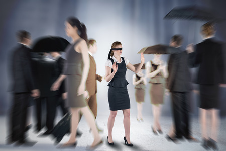 Composite image of redhead businesswoman in a blindfold walking through crowdの写真素材