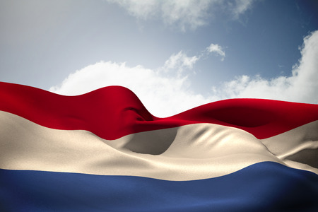 Netherlands flag waving against bright blue sky with cloudsの写真素材