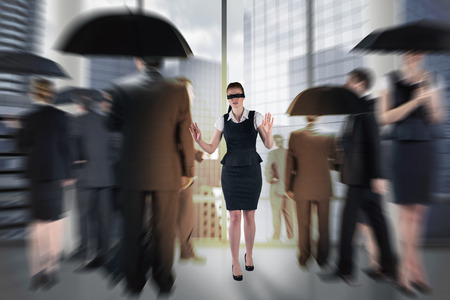 Redhead businesswoman in a blindfold against room with columns and view over cityの写真素材