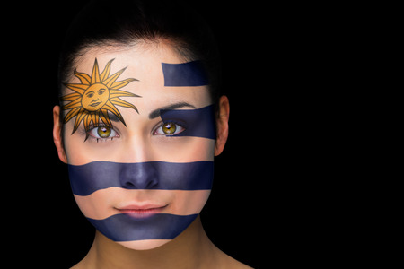 Composite image of uruguay football fan in face paint against blackの写真素材